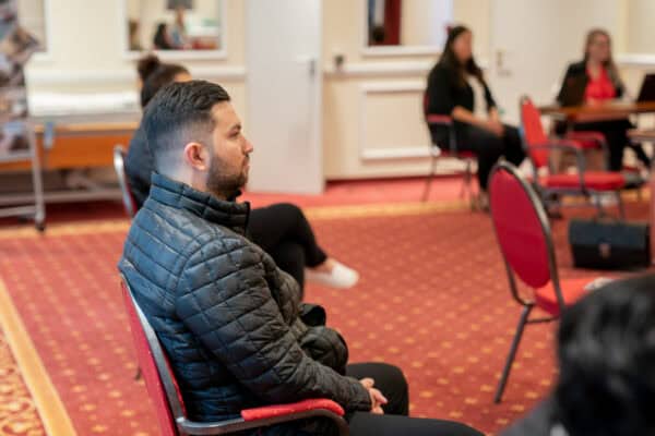 Klimatisierter Mann in schwarzen Jacke sitzt aufmerksam bei einer Präsentation.