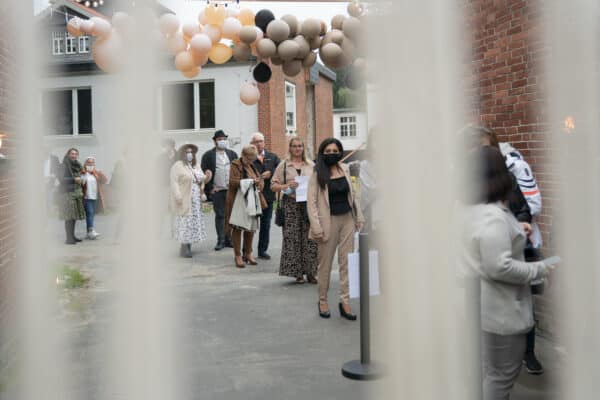 Menschen bei einem Event vor einem Firmengebäude, WarteSchlange, Gesellschaftlicher Anlass, Hahne Holding, Event am Firmenstandort.