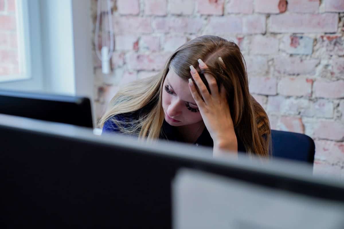 Stressige junge Frau am Arbeitsplatz wegen Überforderung im Büro.