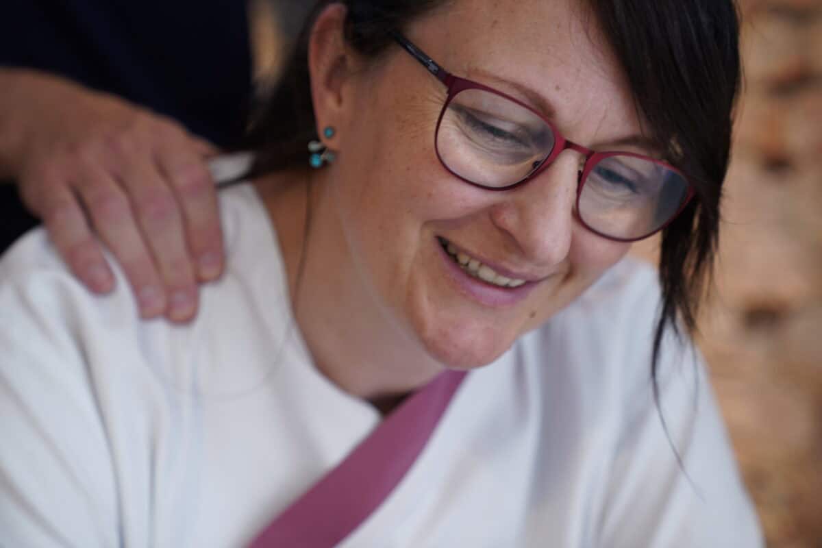 Freundliche Frau mit Brille und weißen Hemd, beim Gespräch bei Hahne Holding in Deutschland.