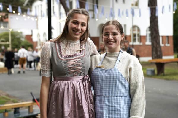 Fröhliche Frauen beim traditionellen Fest, in Trachten gekleidet, vor einem historischen Gebäude.