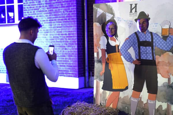 Fotografie eines Mannes, der ein Selfie vor einem Hahne Holding Oktoberfest-Schutzstand macht.