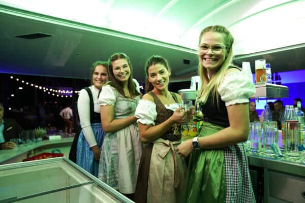 Fröhliche Frauen in Dirndl beim Oktoberfest, feiern und trinken Bier.