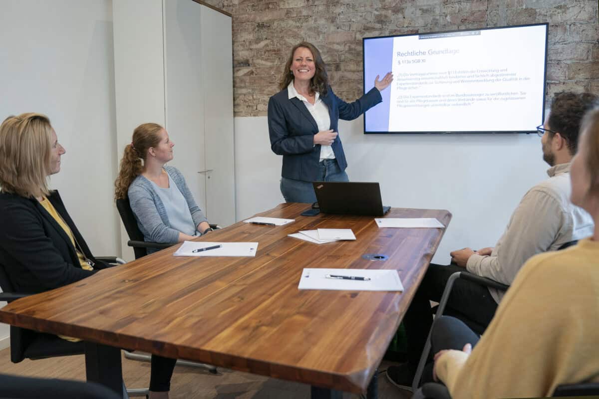 Hahne Holding, Business Meeting, Frau präsentiert rechtliche Grundlagen am Bildschirm, professioneller Workshop, moderne Arbeitsumgebung.