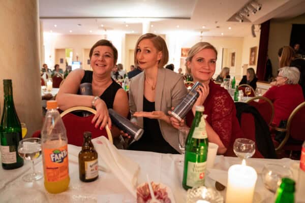 Gelobbytaschen mit Hahne Holding Logo, verpackt in Geschenkrollen, bei festlicher Veranstaltung in elegantem Ambiente.