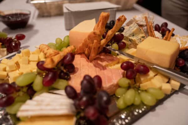 Käsespezialitäten - Käseplatte mit Trauben, Wurst und Crackern, perfekt für gesellige Anlässe.