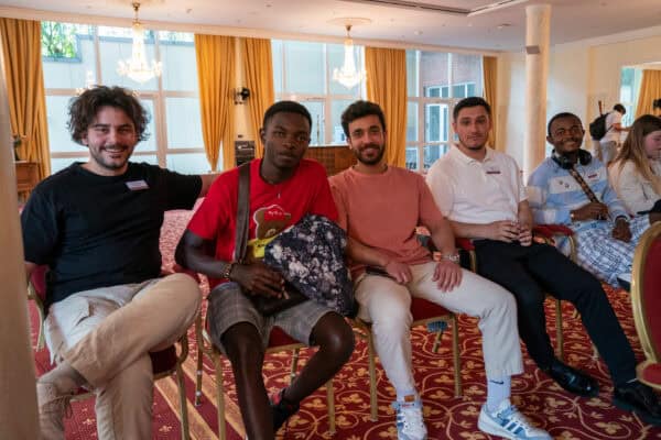 Vielfältige junge Erwachsene bei einem Event im eleganten Raum mit goldenen Vorhängen.