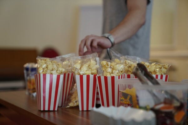 Knabberpopcorn in roten und weißen Streifenbechern auf einem Tisch, Hollywood- oder Kinosnack, für Events oder Kinoabend.