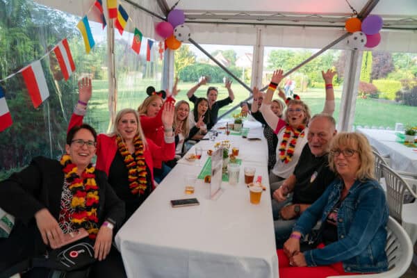 Fröhliche Menschen bei einer Feier mit Deutschlandfahnen und Ballons im Zelt.