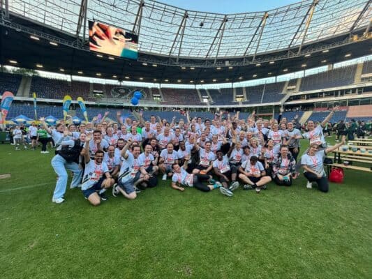 Lustige Erwachsene sammeln sich bei einem Lauf-Event im Stadion, feiern und strahlen vor Freude.
