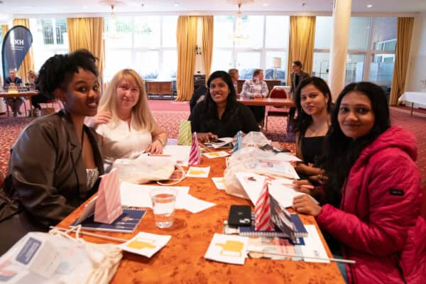 Vielfältige Frauen beim gemeinsamen Treffen in einem hellen, eleganten Veranstaltungsraum.