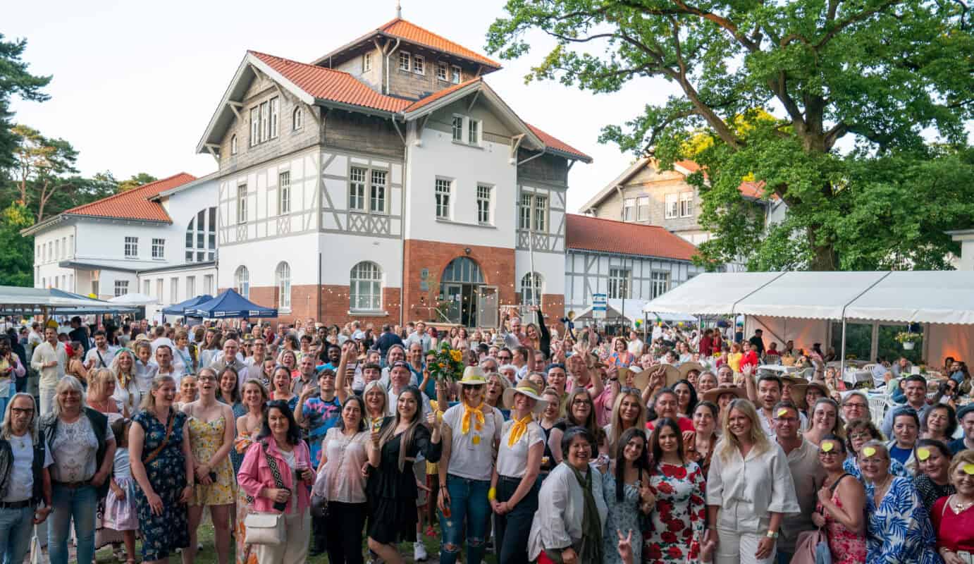 Vielfältiges Fest auf dem Hahne Holding Gelände mit buntem Publikum und zweistöckigem historischen Gebäude im Hintergrund.
