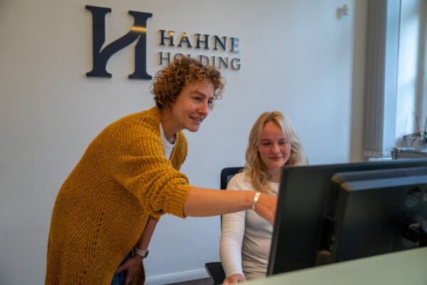 Mitarbeiterin erklärt Ausbildungsmöglichkeiten bei Hahne Holding am Computer.